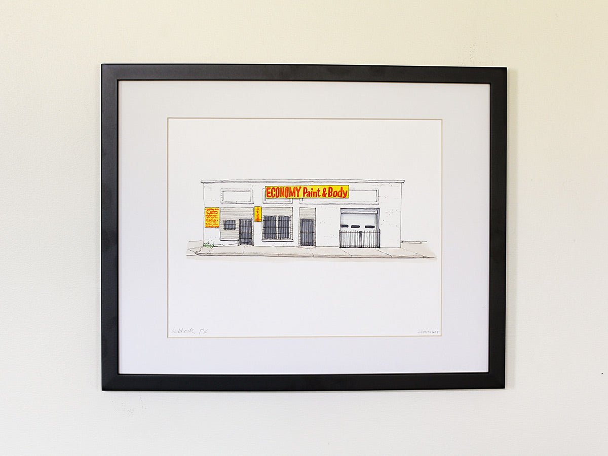 Framed original watercolor art of storefront. Artwork has white matte and a black frame.