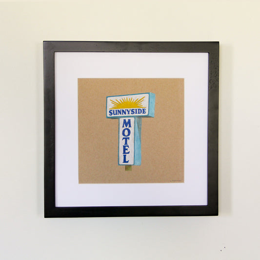 Framed artwork hung on white wall. Colored pencil drawing on tan toned paper of a blue and yellow motel sign with a 2 inch white matte around the art in a black wood frame. 