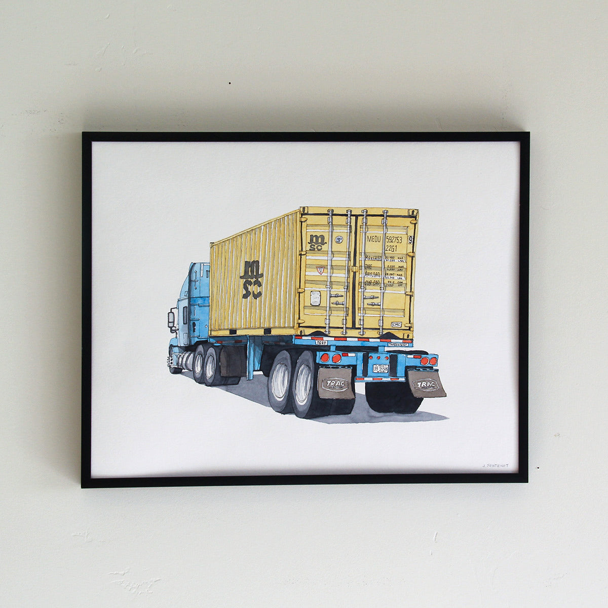 Framed original artwork hung on wall in thin black metal frame. Watercolor painting of yellow container